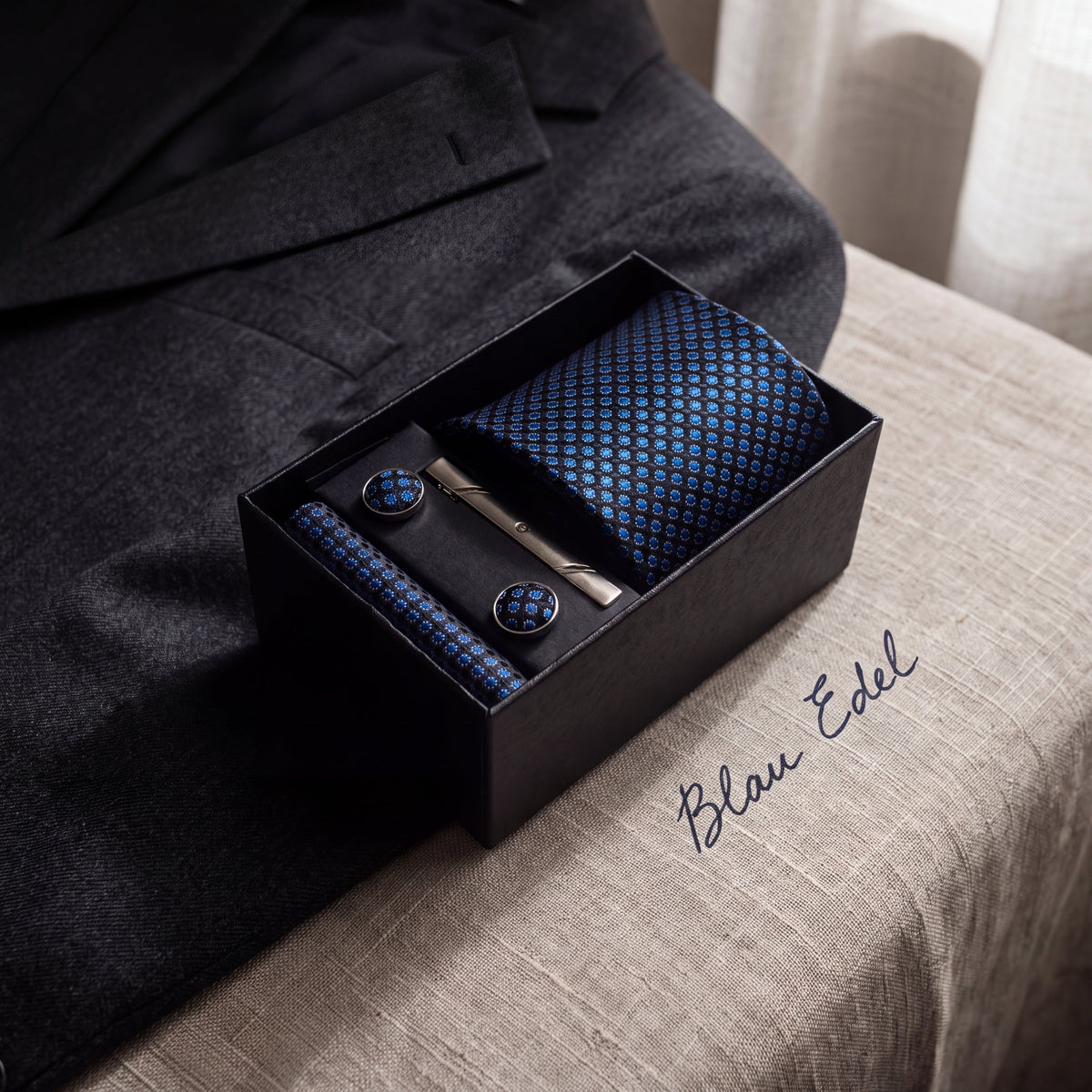 Krawatten-Geschenkset Blau Edel, geöffnete Box auf Leinen neben einem grauen Wollsakko