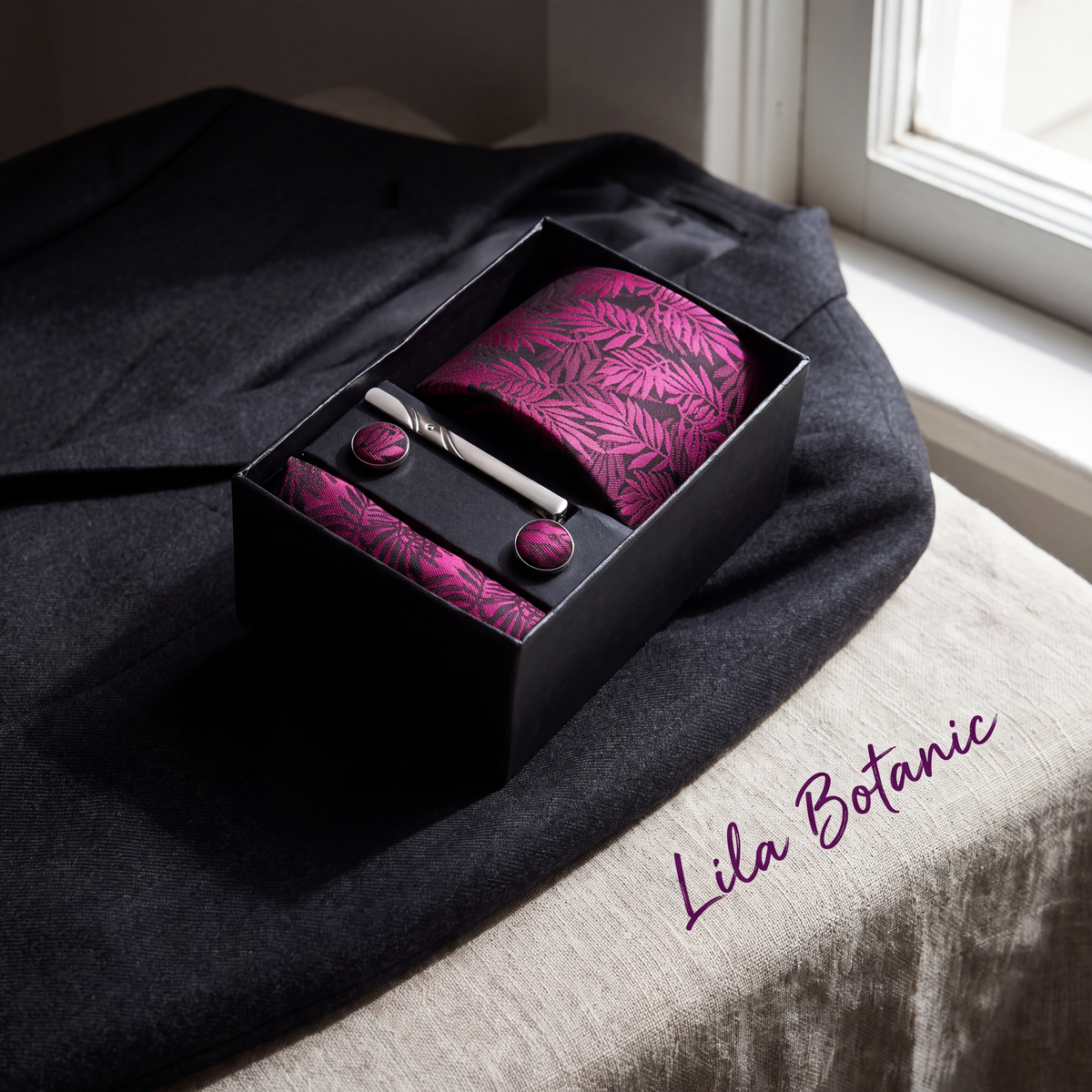 Krawatten-Geschenkset Lila Botanic, geöffnete Box auf einem grauen Wollsakko am Fenster