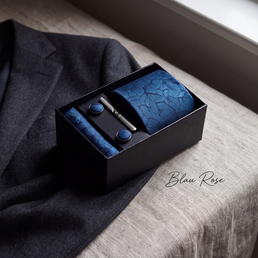 Krawatten-Geschenkset Blau Rose, geöffnete Box auf Leinen neben einem grauen Wollsakko