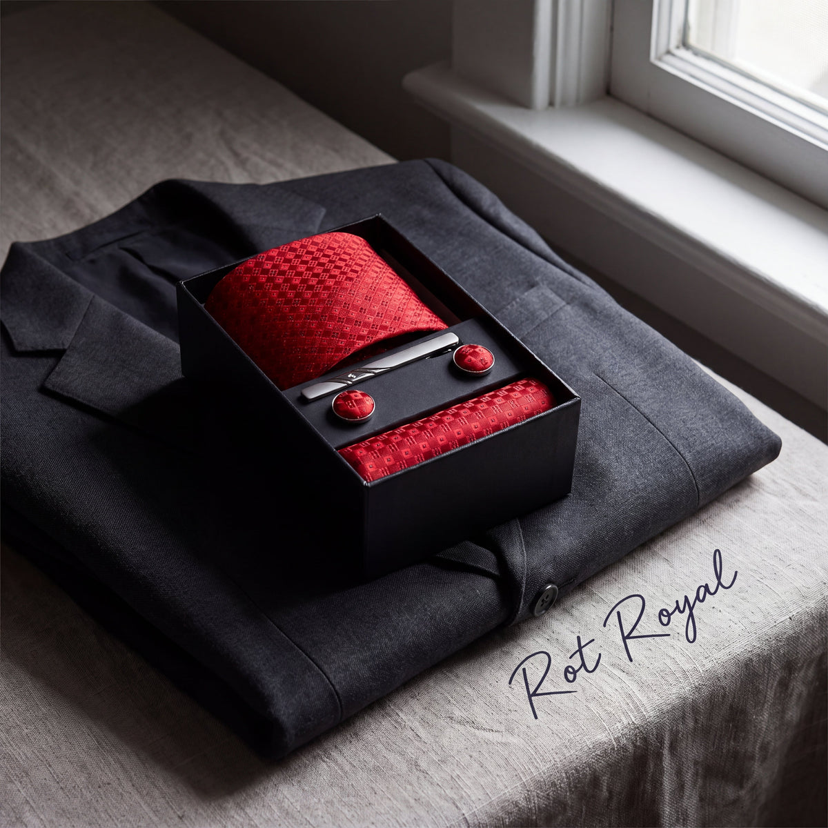 Krawatten-Geschenkset Rot Royal, geöffnete Box auf einem grauen Wollsakko am Fenster