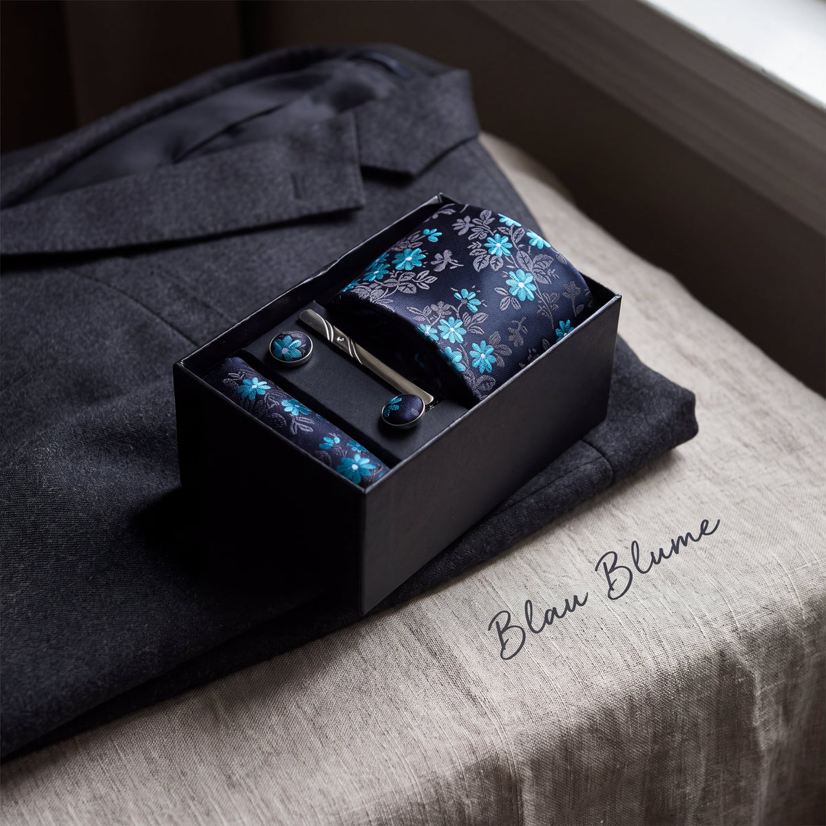 Krawatten-Geschenkset Blau Blume, geöffnete Box auf einem grauen Wollsakko